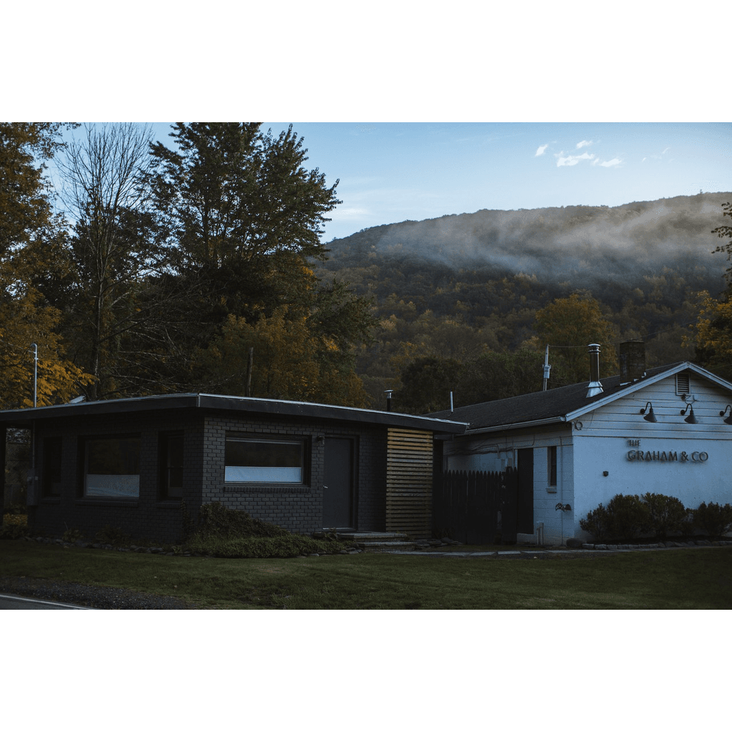 The Graham & Co hotel exterior at dusk with misty Catskills mountains